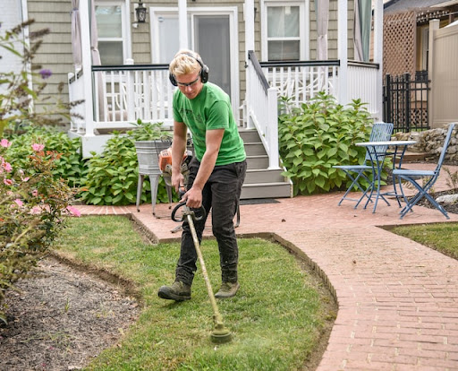 A man in green t-shirt operating a weed wacker 